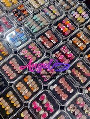 Display of various nail art designs in small plastic cases with 'Angelina Manicure' branding.